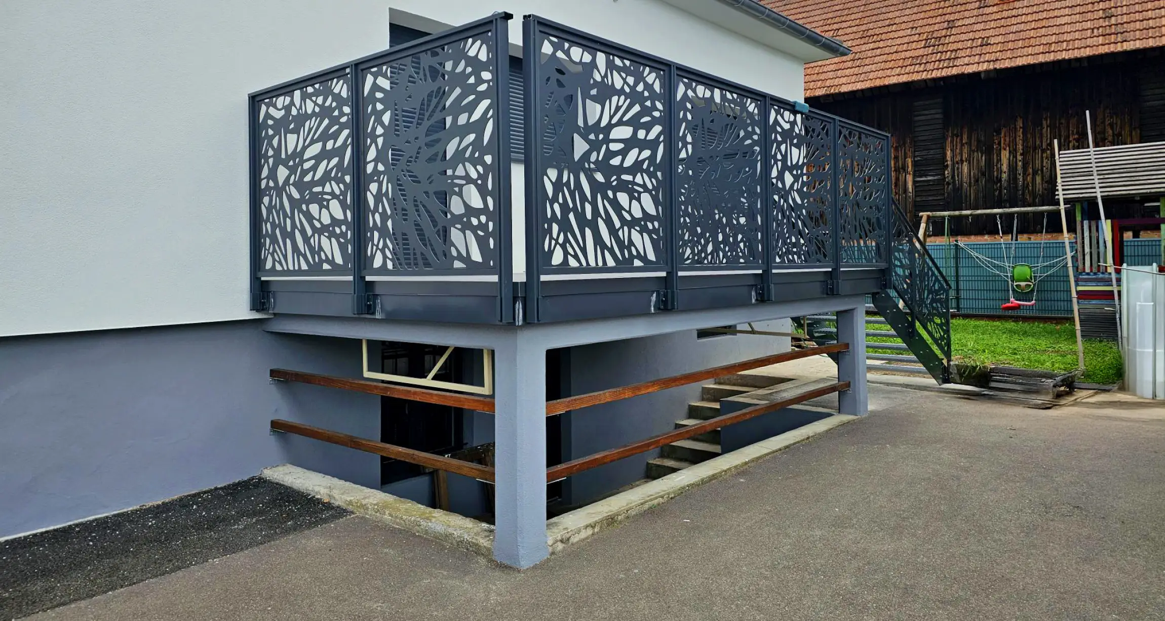 Porte de garage sectionnelle grise anthracite installée sur façade moderne beige avec murs en béton