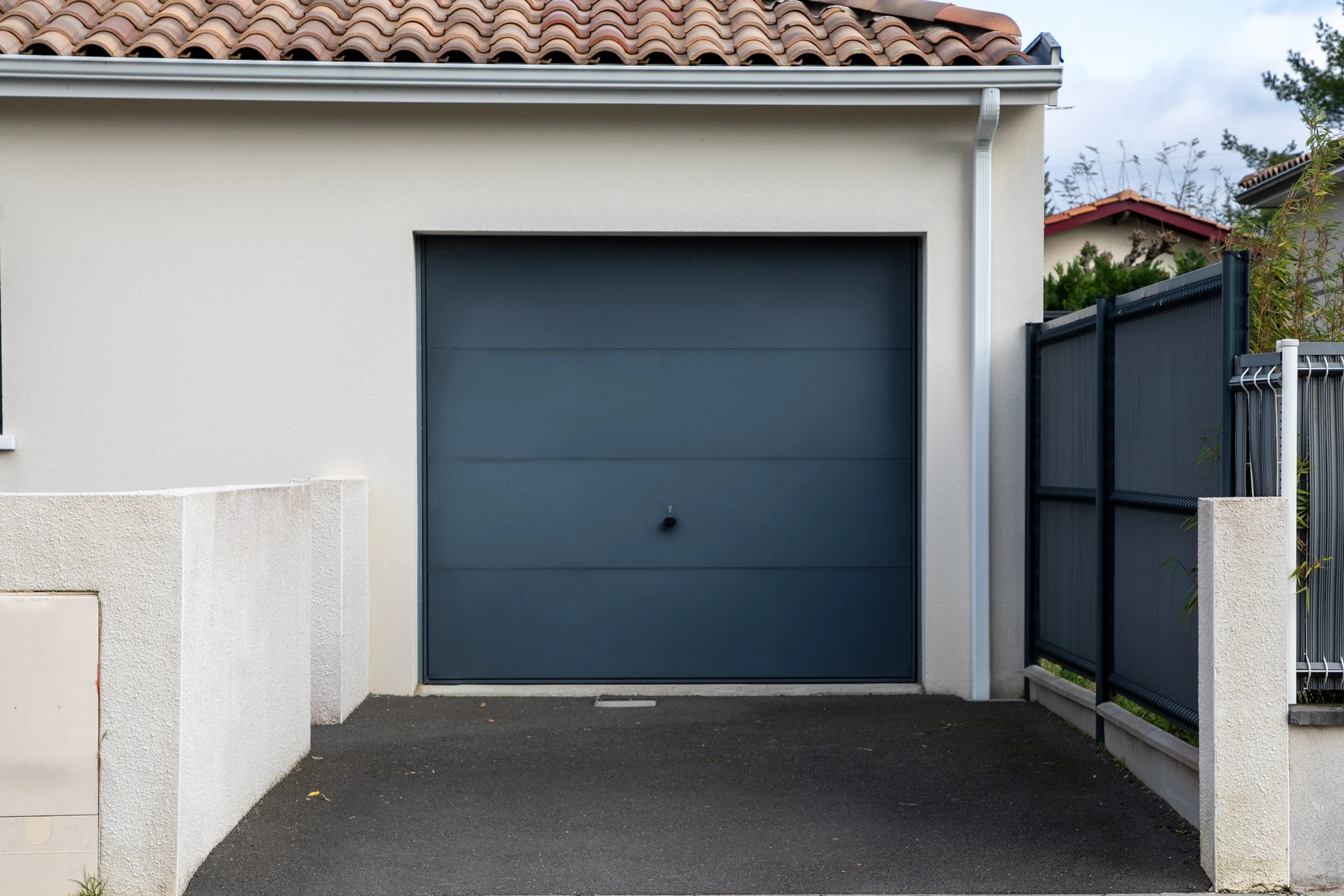 Extérieur résidentiel moderne avec garage individuel à porte sectionnelle gris anthracite