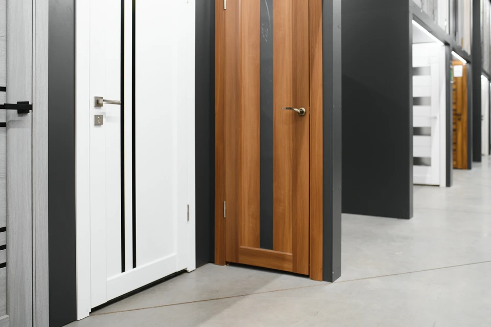 Métallier en atelier travaillant à la main la structure d'une porte d'entrée en acier brut sur un établi, lima ou ciseau à main en action, détails de la finition artisanale de la serrure ou de la ferronnerie, lumière naturelle d'atelier mettant en évidence la texture du métal et les marques du façonnage manuel.